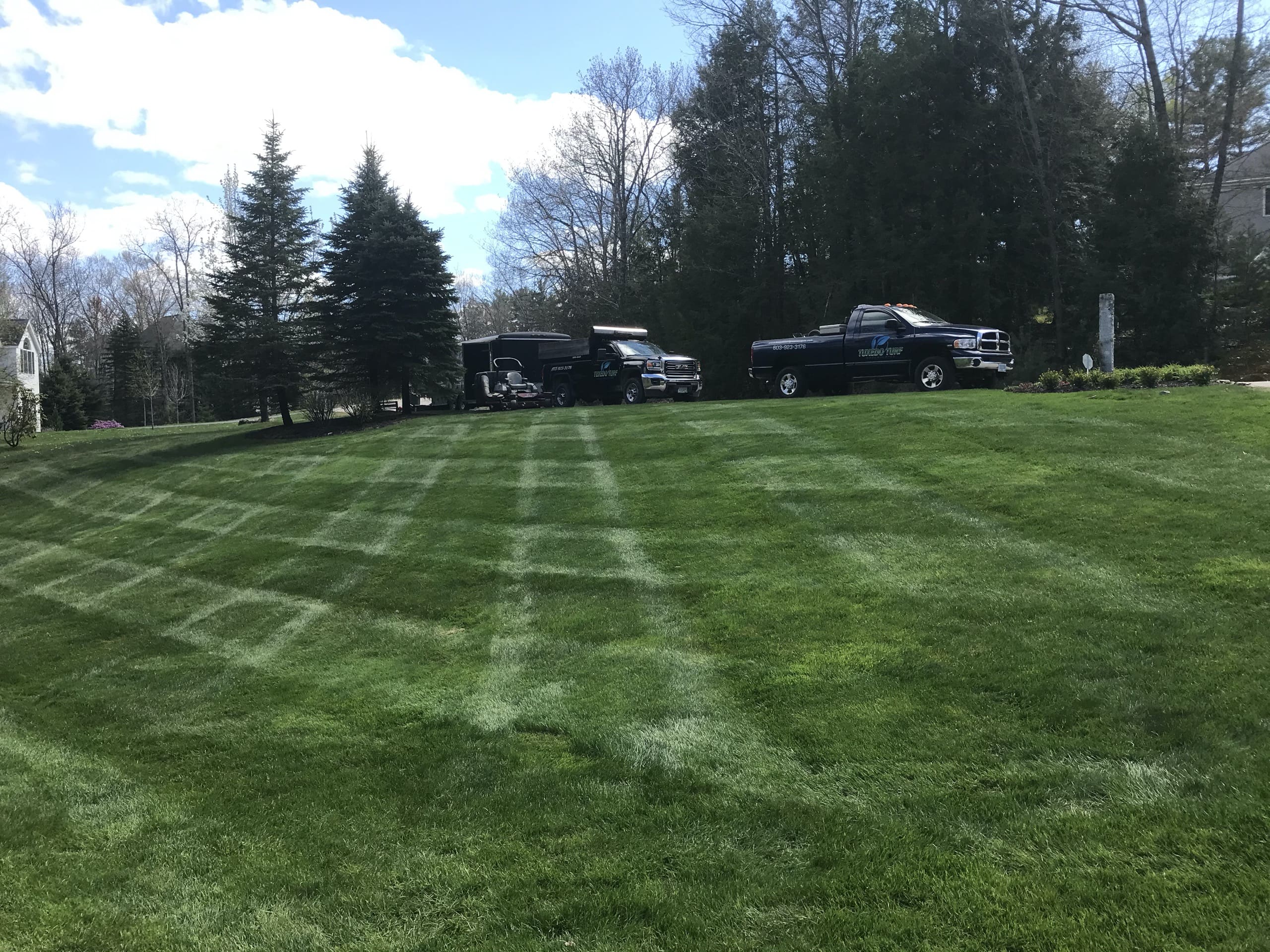 Landscaping truck parked on a hill with nicely mowed lawn in foreground
